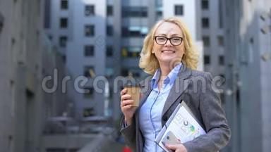 女企业工人自由呼吸，手拿咖啡杯和工作文件